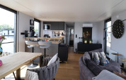 Intérieur moderne de la péniche 'Kohlenpott' aux Pays-Bas, avec salon, cuisine et vue sur l’eau.