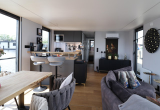 Interior moderno de la casa flotante 'Kohlenpott' en los Países Bajos, con sala, cocina y vistas al agua.