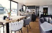 Moderne og lys stue og køkken på husbåden «Kohlenpott» i Holland, med store vinduer og hygge.