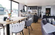 Salon et cuisine modernes et lumineux à bord de la péniche «Kohlenpott» aux Pays-Bas, grandes fenêtres.