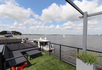 Vue depuis la péniche Kohlenpott aux Pays-Bas, terrasse, rivière, bateaux et ciel nuageux.