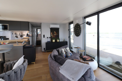 Moderna casa flotante Kohlenpott en los Países Bajos con salón abierto, ventanales y vistas al agua.