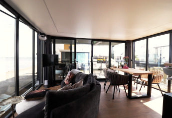 Modernes Wohnzimmer auf Hausboot «Kohlenpott» in den Niederlanden mit großem Fensterblick aufs Wasser.
