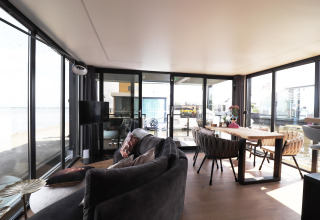 Modernes Wohnzimmer auf Hausboot «Kohlenpott» in den Niederlanden mit großem Fensterblick aufs Wasser.