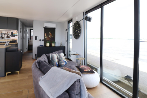 Modernes Wohnzimmer auf Hausboot „Kohlenpott“ in den Niederlanden mit großen Fenstern und Wasserblick.