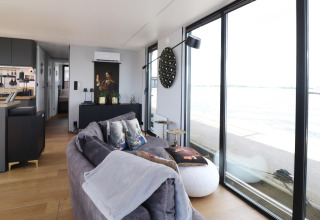 Modernes Wohnzimmer auf Hausboot „Kohlenpott“ in den Niederlanden mit großen Fenstern und Wasserblick.