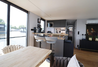Salón y cocina modernos en la casa flotante «Kohlenpott» en los Países Bajos con vista al agua.