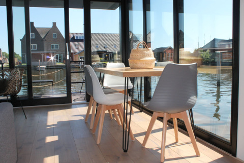 Lichte eethoek op woonboot Boat House Stavoren met grote ramen en uitzicht op het water in Nederland.