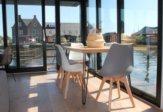 Lichte eethoek op woonboot Boat House Stavoren met grote ramen en uitzicht op het water in Nederland.
