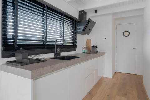 Moderne keuken in een woonboot genaamd Boat House Stavoren in Nederland met strak en licht interieur.