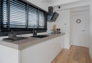 Moderne keuken in een woonboot genaamd Boat House Stavoren in Nederland met strak en licht interieur.