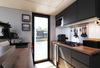 Interior de cocina moderna en la casa flotante «Kohlenpott» en Países Bajos, con vista al agua por la puerta.