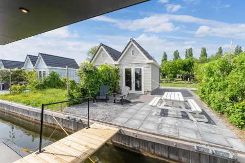 Huis met terras, picknicktafel en uitzicht op de gracht bij Boat House Stavoren, Nederland, zonnig.