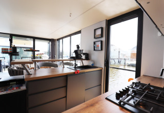 Moderne Küche auf dem Hausboot «Kohlenpott» in den Niederlanden mit Blick aufs Wasser durch große Fenster.