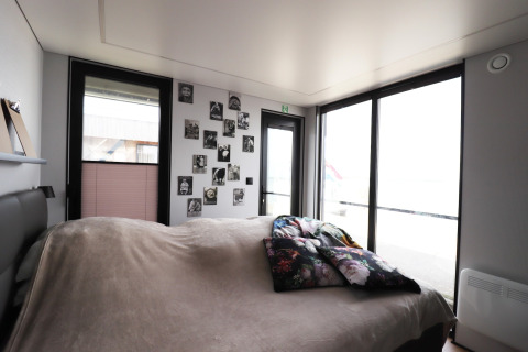 Schlafzimmer auf dem Hausboot «Kohlenpott» in den Niederlanden mit großen Fenstern und Wandfotos.