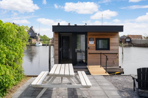 Modern woonboot met houtlook, picknicktafel bij het water, Boat House Stavoren, Nederland.