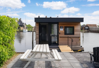 Modern woonboot met houtlook, picknicktafel bij het water, Boat House Stavoren, Nederland.
