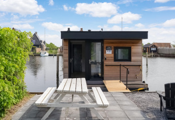 Hausboot mit moderner Holzfassade und Picknicktisch am Wasser, Boat House Stavoren, Niederlande.