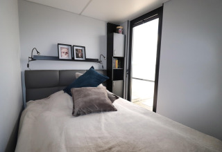 Schlafzimmer im Hausboot 'Kohlenpott' in den Niederlanden mit Bett, Kissen, Regal und Tageslicht.