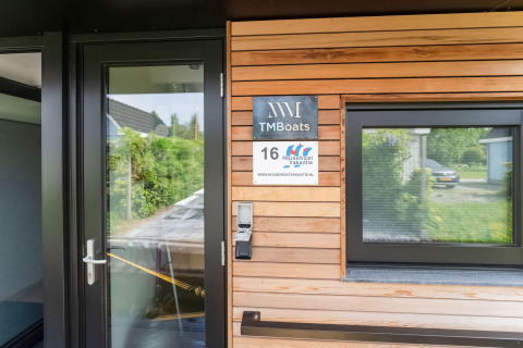 Ingang van moderne woonboot met TMBoats-bord, houten gevel en raam in Stavoren, Nederland.