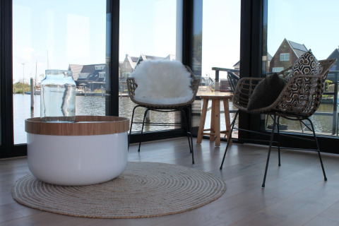 Moderne woonkamer op een woonboot in Stavoren, Nederland, met designstoelen en uitzicht op het water.