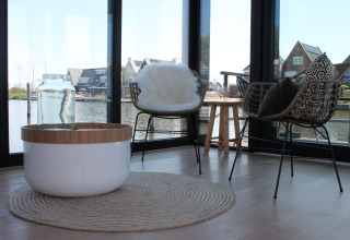 Moderne woonkamer op een woonboot in Stavoren, Nederland, met designstoelen en uitzicht op het water.