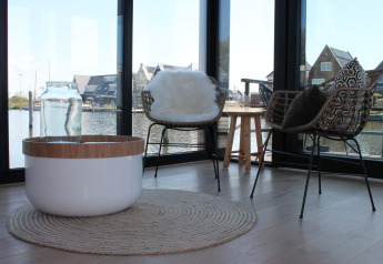 Modernes Wohnzimmer auf einem Hausboot in Stavoren, Niederlande, mit stilvollen Stühlen und Seeblick.