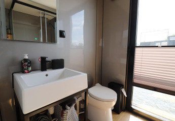Salle de bain moderne avec lavabo, miroir et toilettes sur la péniche «Kohlenpott» aux Pays-Bas, fenêtre ensoleillée.
