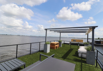 Terrasse sur le toit de la péniche «Kohlenpott» aux Pays-Bas, pelouse artificielle et vue sur l’eau.