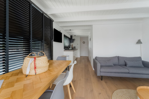 Moderne woonkamer op woonboot Boat House Stavoren in Nederland met houten vloer en grijze bank.
