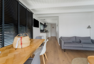 Moderne woonkamer op woonboot Boat House Stavoren in Nederland met houten vloer en grijze bank.