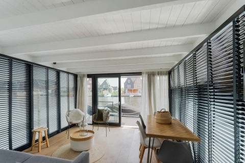 Moderne woonkamer op een woonboot met grote ramen en uitzicht op het water in Stavoren, Nederland.