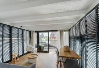 Moderne woonkamer op een woonboot met grote ramen en uitzicht op het water in Stavoren, Nederland.