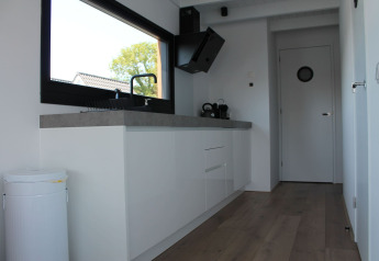 Modernes Kücheninterieur auf einem Hausboot mit weißen Schränken und großem Fenster in Stavoren, Niederlande.