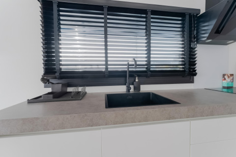 Moderne keuken met zwarte kraan en jaloezieën op een woonboot genaamd Boat House Stavoren in Nederland.