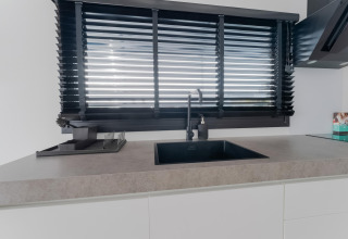 Moderne keuken met zwarte kraan en jaloezieën op een woonboot genaamd Boat House Stavoren in Nederland.