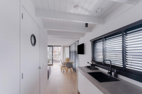 Licht, modern interieur van woonboot Boat House Stavoren in Nederland met keuken en eethoek.
