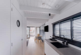 Licht, modern interieur van woonboot Boat House Stavoren in Nederland met keuken en eethoek.