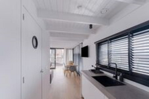 Licht en modern interieur van woonboot Boat House Stavoren in Nederland met keuken en eethoek.