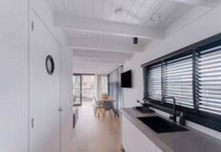 Licht en modern interieur van woonboot Boat House Stavoren in Nederland met keuken en eethoek.