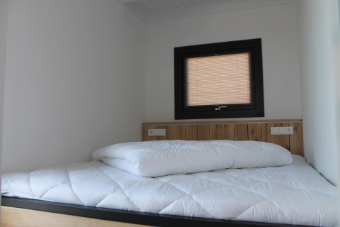 Slaapkamer in Boat House Stavoren, Nederland, met wit beddengoed en een klein raam boven het bed.