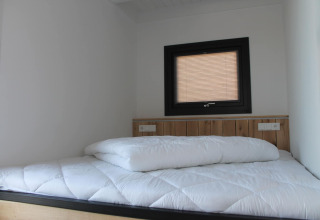 Slaapkamer in Boat House Stavoren, Nederland, met wit beddengoed en een klein raam boven het bed.