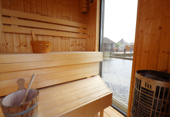 Vue intérieure du sauna sur la péniche 'Kohlenpott' aux Pays-Bas, donnant sur l'eau depuis la fenêtre.