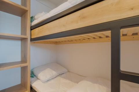 Stapelbedden met lichte houten frames en plankenkast in een kamer van Boat House Stavoren in Nederland.