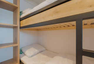 Stapelbedden met lichte houten frames en plankenkast in een kamer van Boat House Stavoren in Nederland.