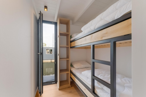 Moderne stapelbedden in Boat House Stavoren, een woonboot in Nederland, met uitzicht op het water.