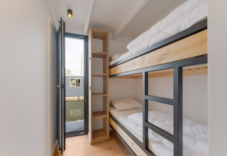 Moderne stapelbedden in Boat House Stavoren, een woonboot in Nederland, met uitzicht op het water.