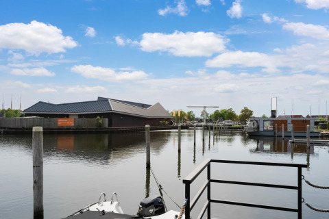 Uitzicht vanaf woonboot Boat House Stavoren in Nederland met steiger, boten en modern gebouw.
