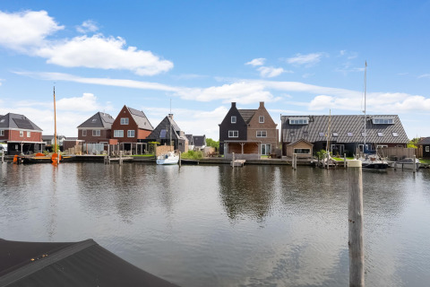 Uitzicht vanaf een woonboot in Stavoren, Nederland, met traditionele huizen en boten aan het kanaal.