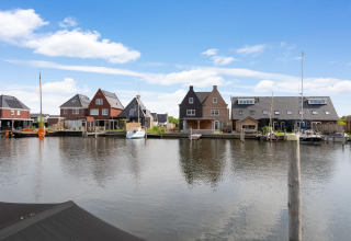 Uitzicht vanaf een woonboot in Stavoren, Nederland, met traditionele huizen en boten aan het kanaal.